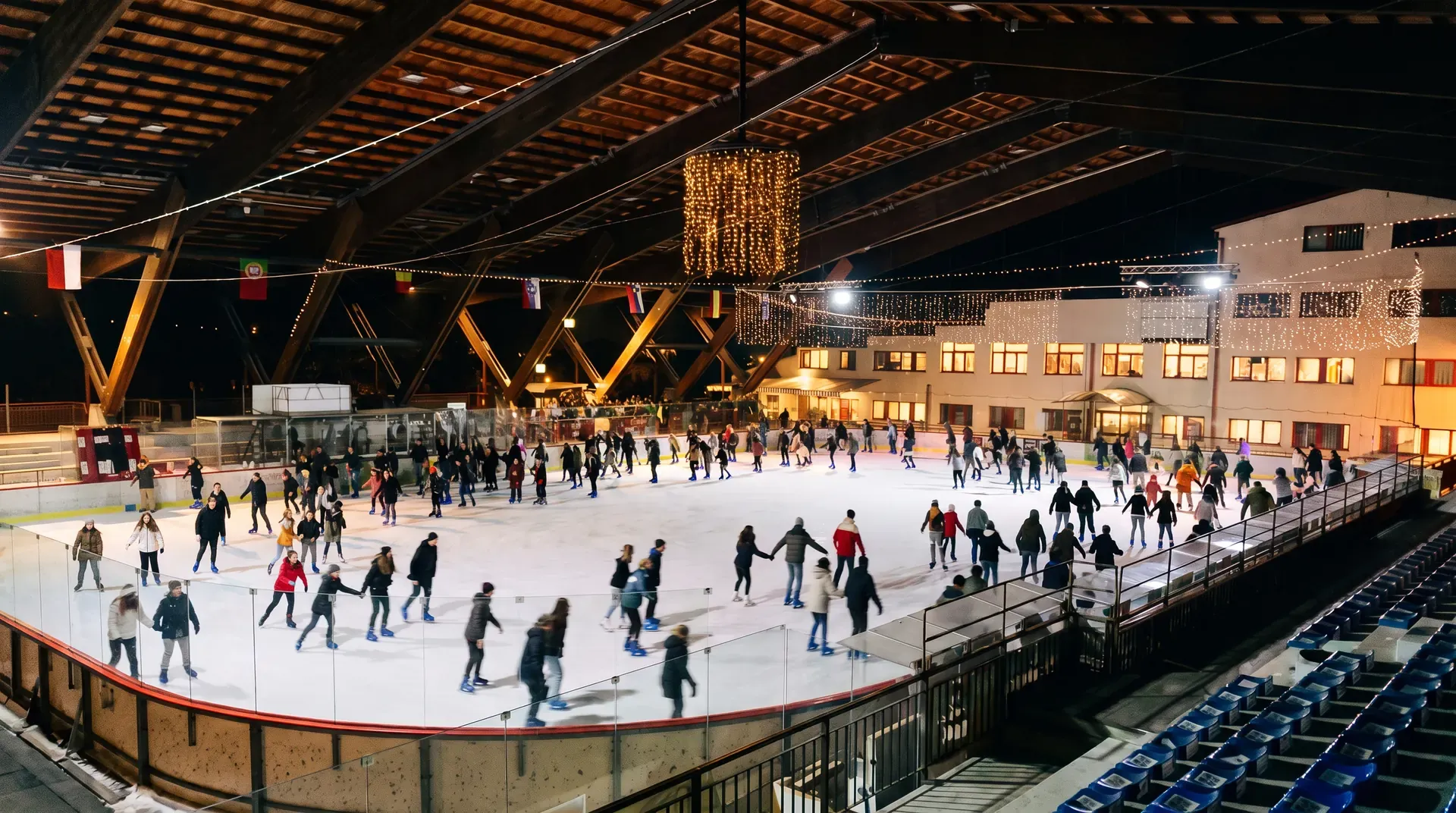 La pista piena di sera, sotto le travi di legno del palazzetto.